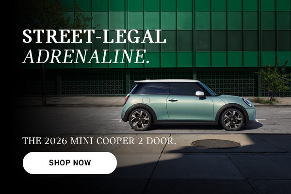 Mint green MINI Cooper 2-door parked on a city street with building backdrop, with ad text promoting the 2026 model and a “Sh