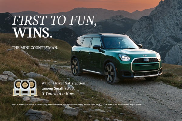 Front passenger side view of a green MINI Countryman  driving on a mountainous road.