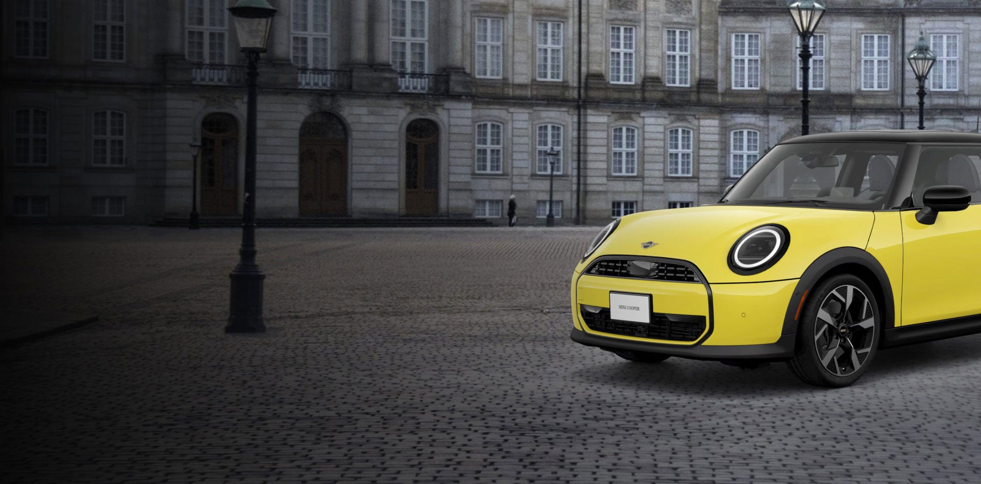 ¾ Front side view of a MINI Cooper Oxford Edition parked on a brick street in front of a building.